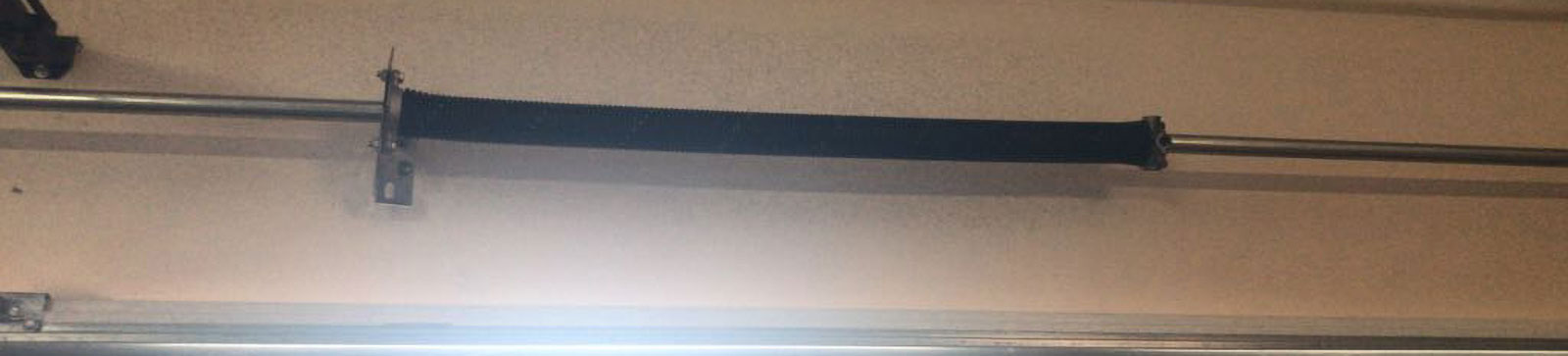 Close-up of snapped torsion spring on residential garage door in Mound, MN before spring replacement.