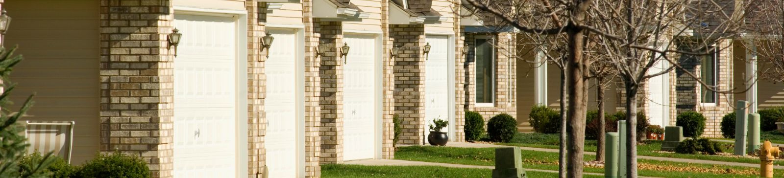 Row of suburban homes in Chaska, MN featuring well-maintained white garage doors and tidy front yards, representing Garage Door Repair services.