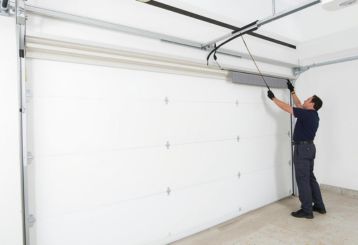 Professional technician installing a new white garage door in Chaska, MN residential garage