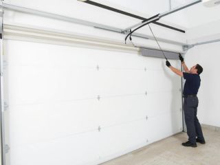 Professional technician installing a new white garage door in Chaska, MN residential garage